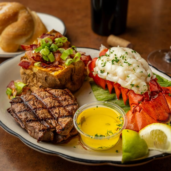 Sterling's surf and turf with steak, lobster tail, loaded baked potato, and melted butter.