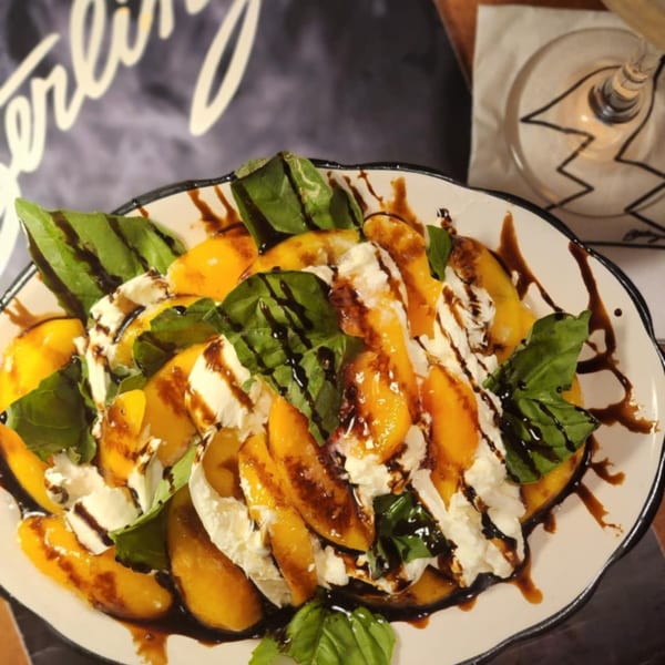 Sterling's Restaurant breakfast dish with sliced peaches, whipped cream, basil, and balsamic glaze.