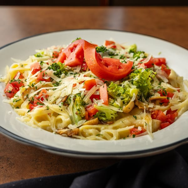 Fettuccine pasta topped with fresh tomatoes, broccoli, shredded cheese, and herbs at Sterling's.