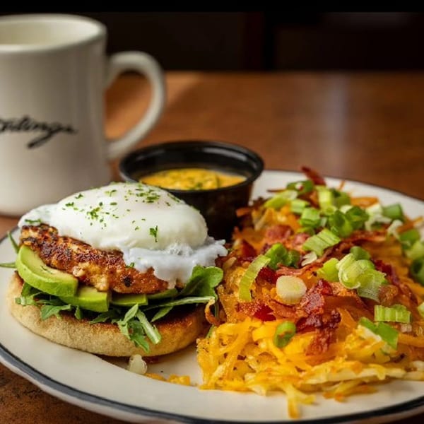 Sterling's breakfast plate with a poached egg sandwich, hash browns, and a side of cheese sauce.