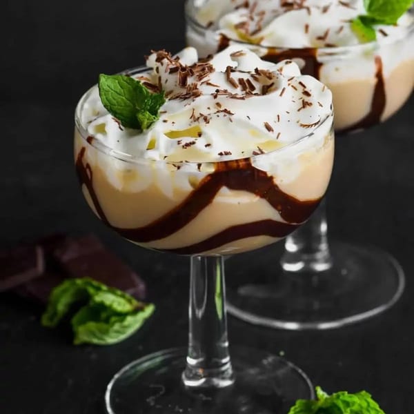 Two Sterling's Restaurant breakfast parfaits with whipped cream, chocolate shavings, and mint garnish.